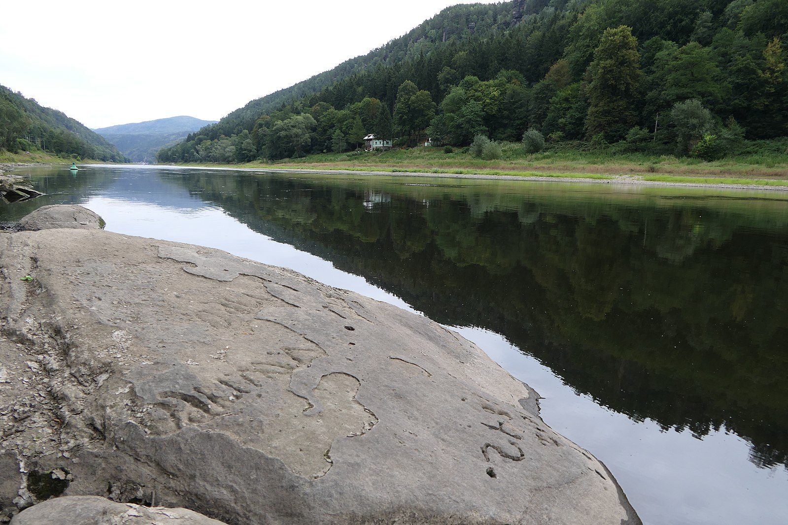 A hunger stone interrupts a peaceful river scene.
