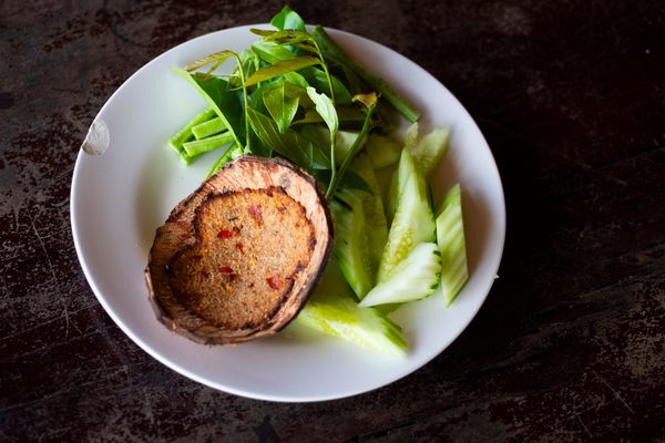 Crab meat and shrimp get pounded in a mortar and pestle with grated coconut, shrimp paste, chili and aromatics, smeared on the inside of a coconut shell and grilled until fragrant,