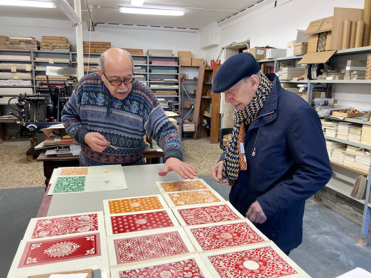 Olbi (right) checks the designs of his covers before they are glued onto binded pages. 