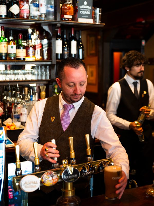 Bartenders pour up a particularly smooth pint of Guinness at The Guinea.