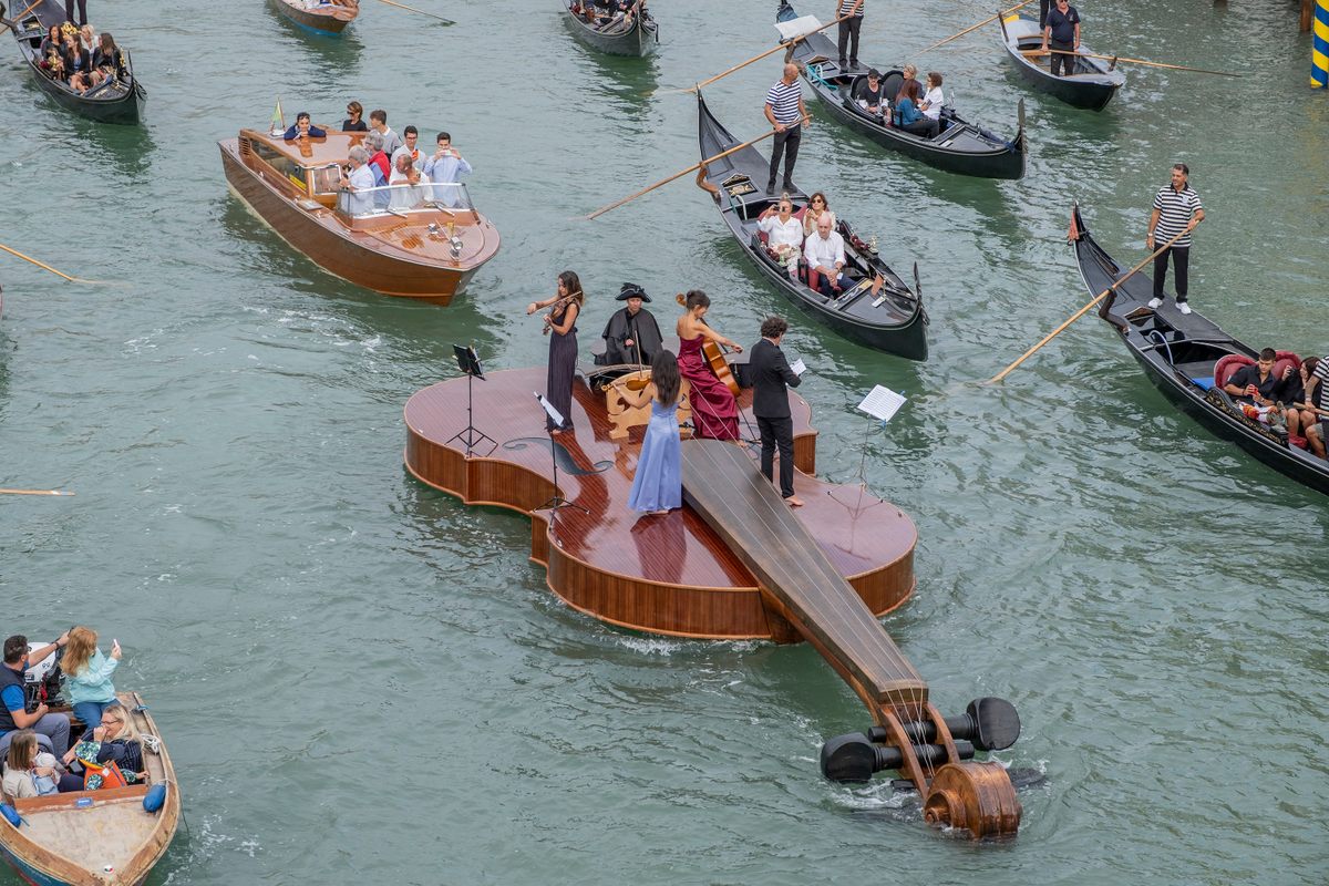 A 39-foot violin-shaped boat with a string quartet on board, conceived by Venetian artist Livio De Marchi, floats near Venice's Accademia Bridge on September 18, 2021. 