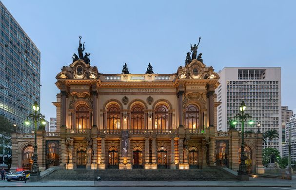 The exterior of a large, elaborate theatre at dusk