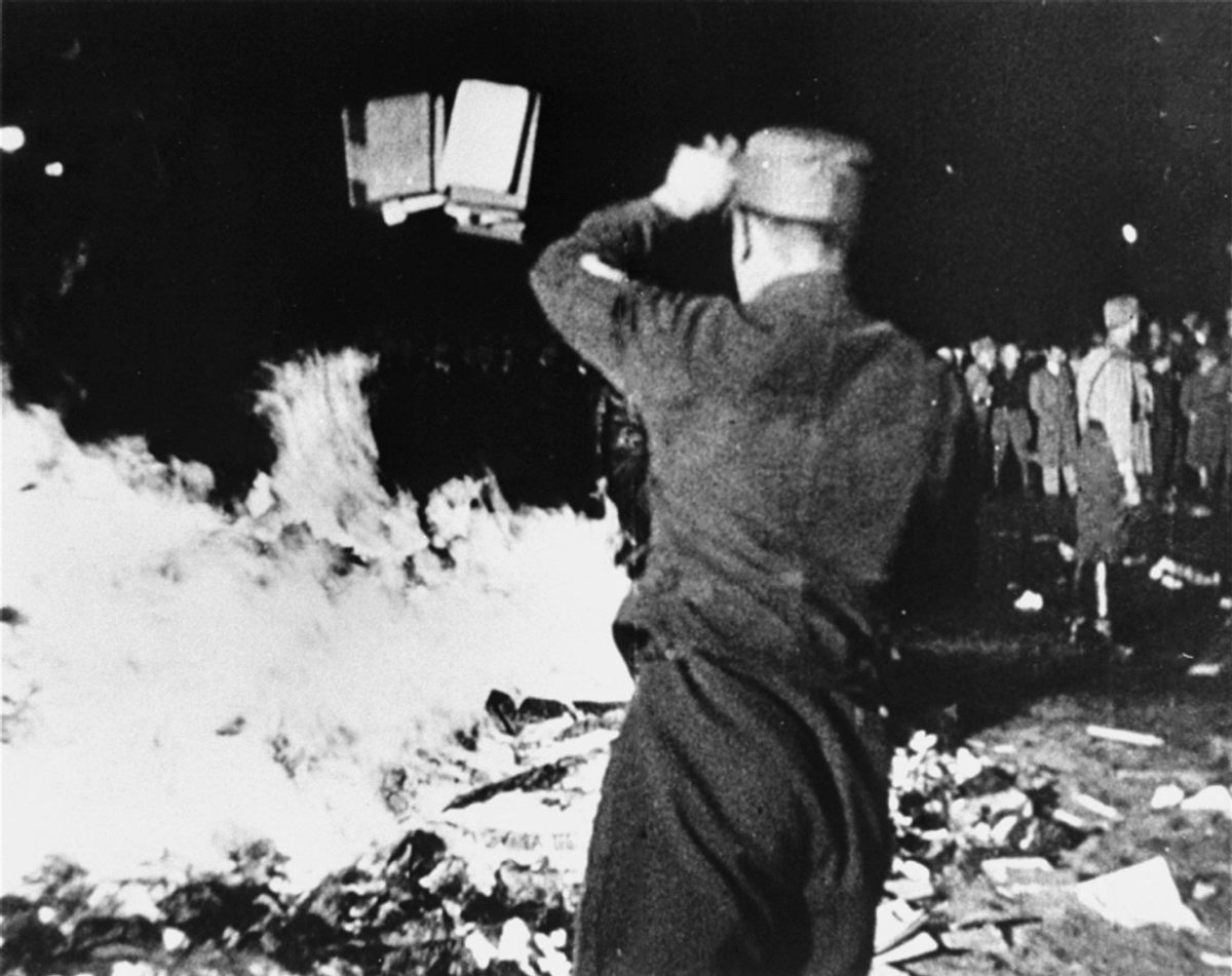A member of the paramilitary Nazi Sturmabteilung throws confiscated books into a bonfire during the public burning of "un-German" books in Berlin in 1933.