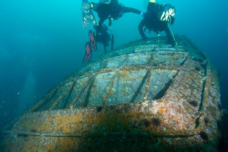 Divers climb the smokestack of what was once the USS Oriskany.