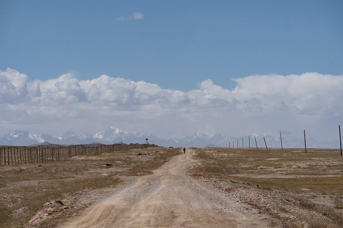 In the distance, Dmitriy Makarov from Kazakhstan rides along the Chinese border in Kyrgyzstan.