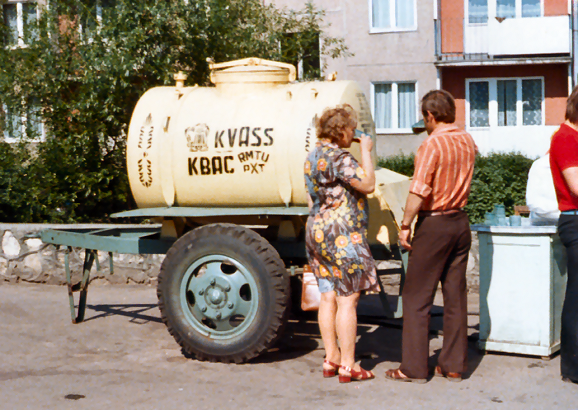 A 1977 photograph shows a couple drinking kvass from communal mugs alongside an iconic yellow barrel.