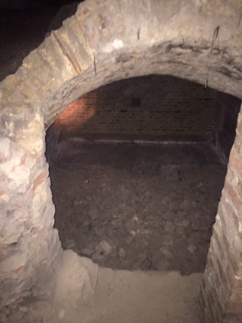 The far brick wall of the former wine cellar hides the tomb.