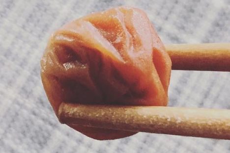 A lone umeboshi between chopsticks.
