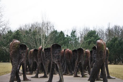 A crowd of headless sculptures stands in the park.
